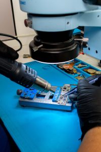 Electrónica en General Close-up of a technician using tools on a circuit board under a microscope.